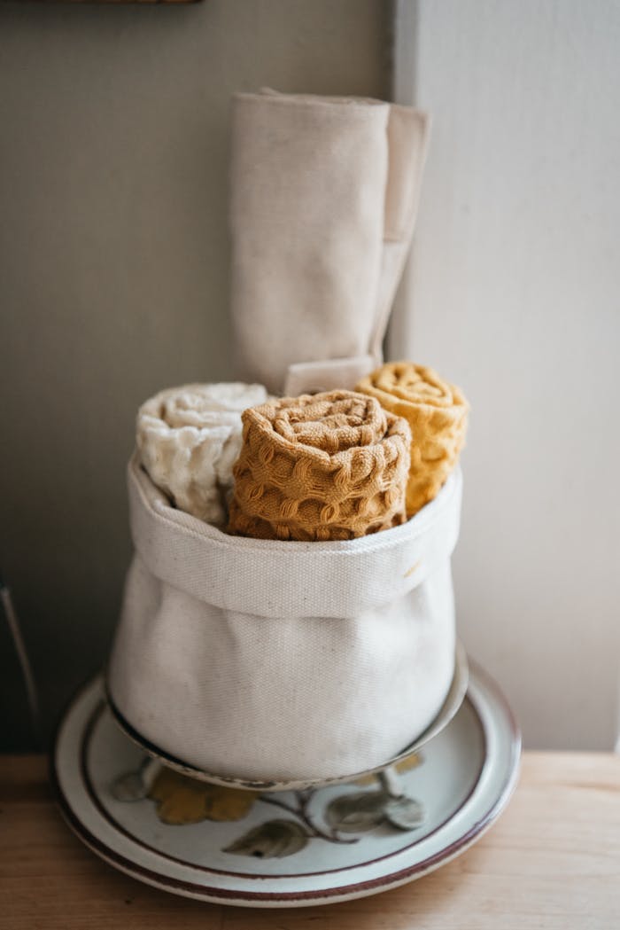 Cotton kitchen towels neatly arranged in a rustic sackcloth basket for a cozy touch.